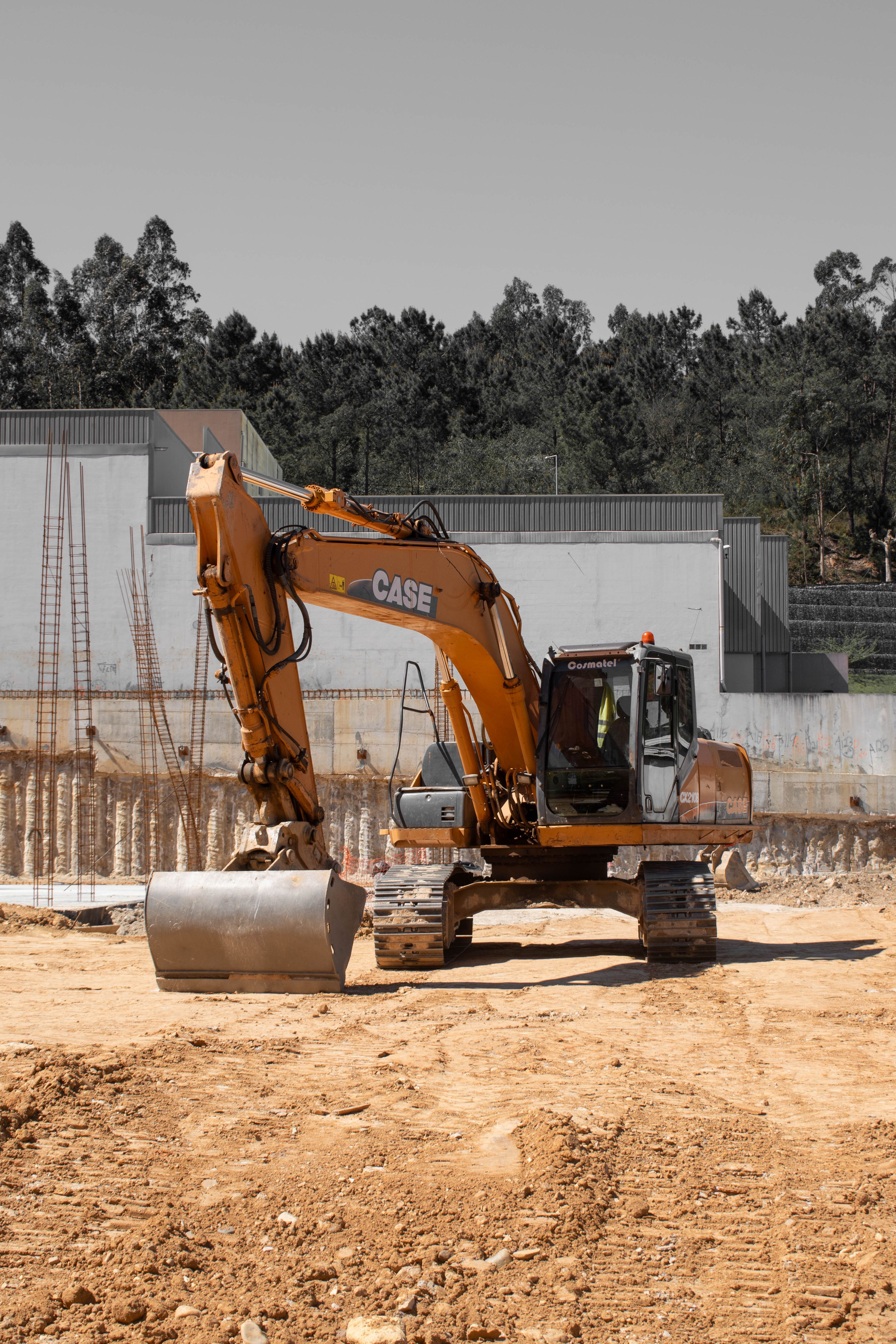 Excavator on a construction site with forested hills in the background