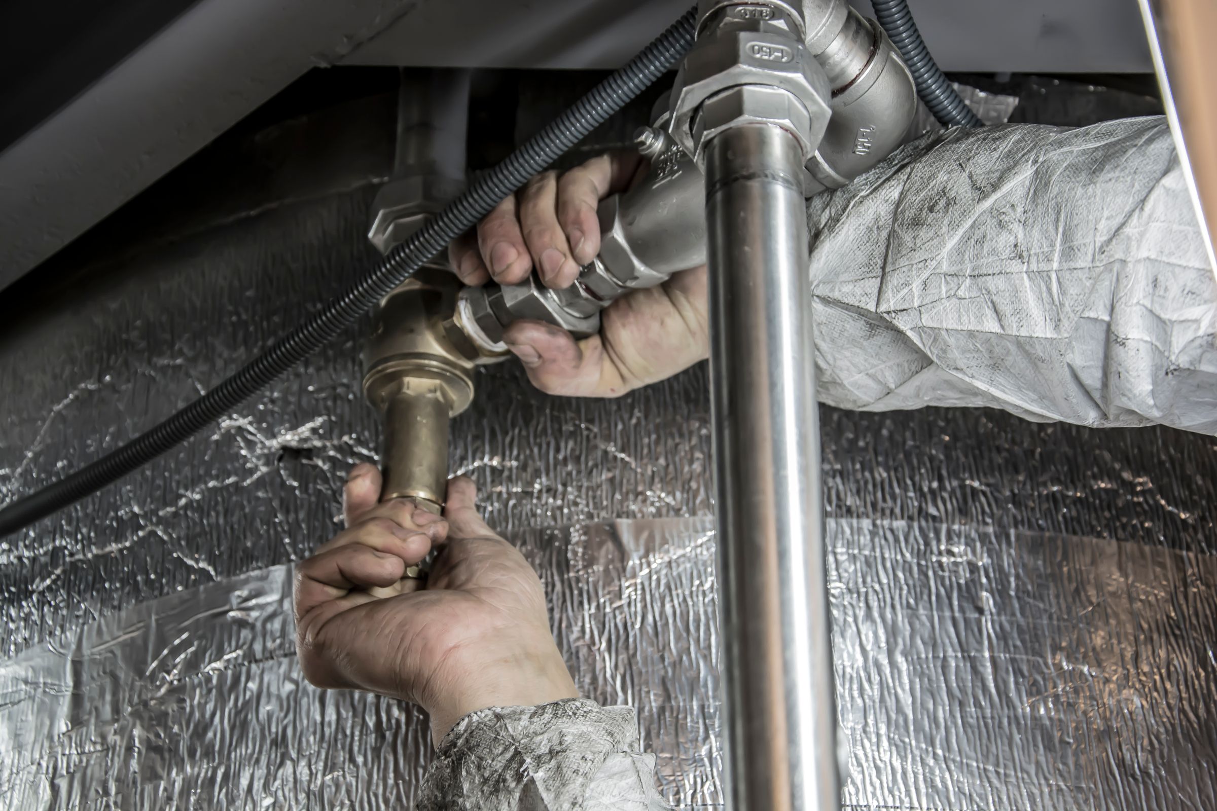 Plumber's hands installing steel pipes outdoors